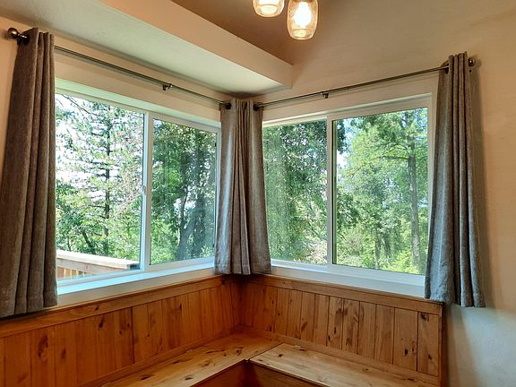Corner windows in dinning showing the view of oaks, pine, and other native trees.