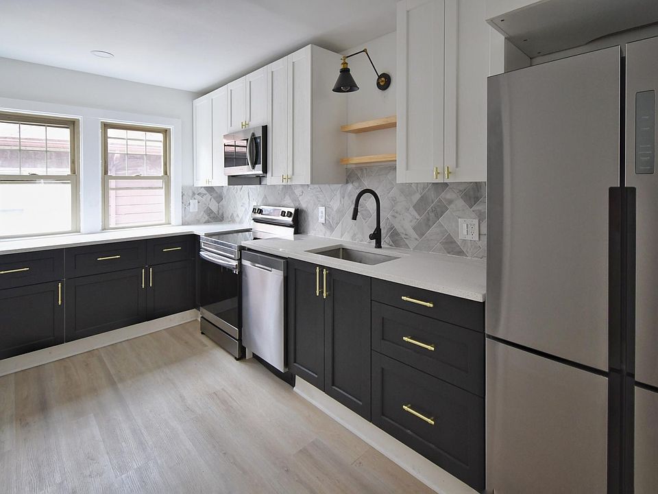 Modern kitchen with brand new stainless steel appliances including electric stove, refrigerator, microwave and dishwasher