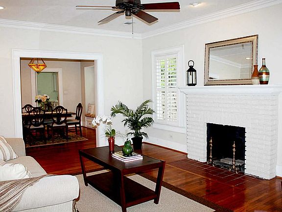Elegant living room with gleaming hardwood floors, wood burning fireplace and ample windows to let i