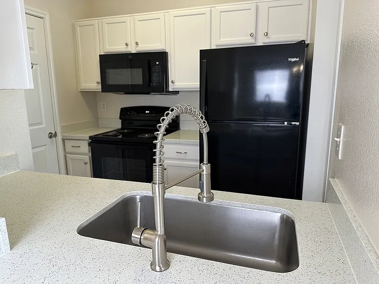 Modern kitchen with sleek black appliances and elegant white cabinetry, accented by quartz countertops and a stylish stainless steel faucet. Modern kitchen with sleek black appliances and elegant white cabinetry, accented by quartz countertops and a styli