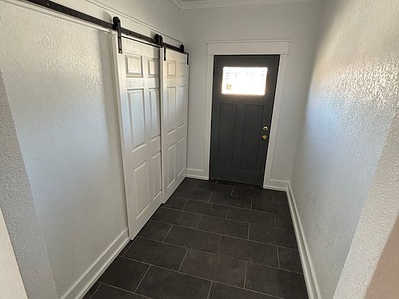 Large mudroom with laundry room behind double doors. Tile floors.