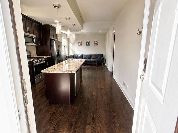Open-concept kitchen with granite island, stainless appliances, and pendant lighting flowing into a shared lounge area.