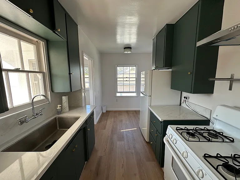 Newly renovated kitchen. Solid wood painted cabinets and drawers, new quartz countertops, new luxury vinyl flooring, new range hood, new sink and faucet.