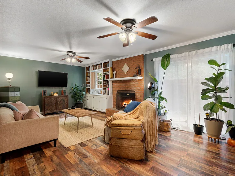 Den / Living room, featuring two built-in bookcases, a gas starter and wood burning fireplace, and external sliding doors to the back patio