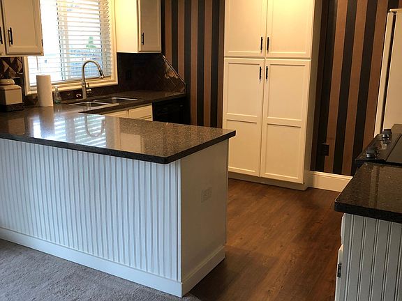 Kitchen showing granite counters, pantry, dishwasher and new flooring