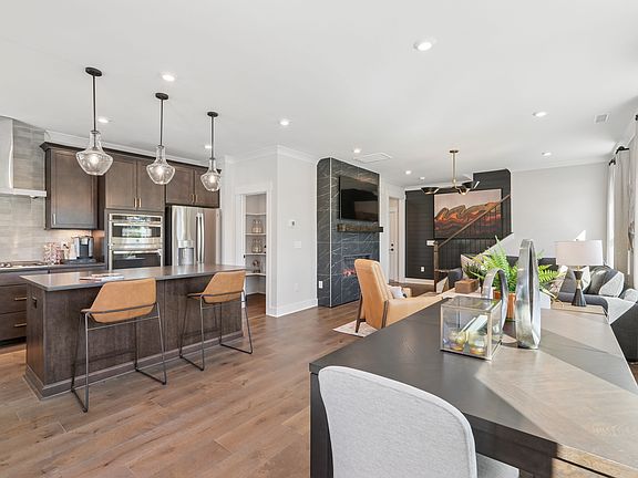 A modern and spacious kitchen with a dining area, featuring dark wood cabinets, pendant lighting, an