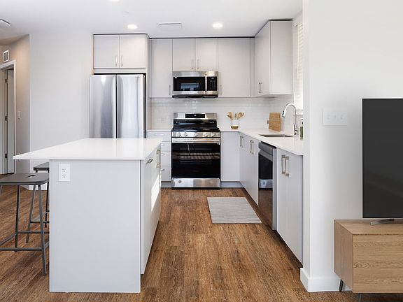 Kitchen with stainless steel appliances, white quartz countertop, light grey cabinetry, and hard surface flooring