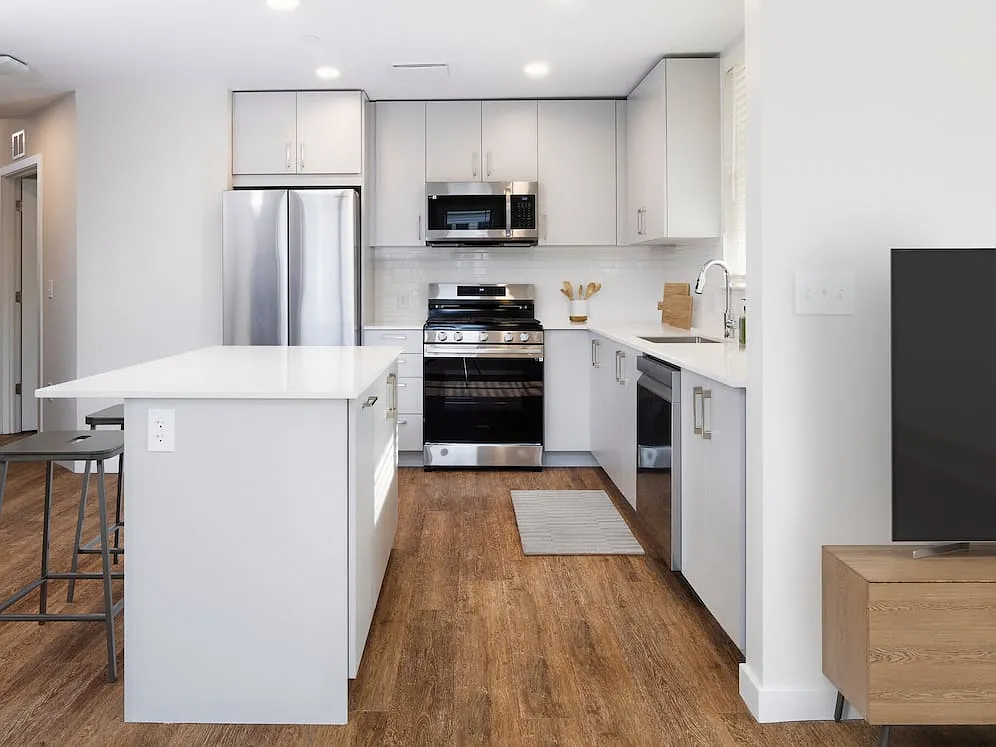 Kitchen with stainless steel appliances, white quartz countertop, light grey cabinetry, and hard surface flooring - Kanso Milford