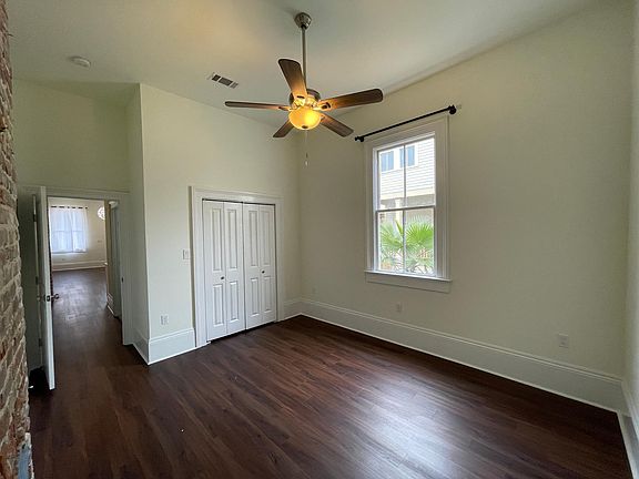 Large bedroom with ceiling fan and big closet. The bedroom has a decoratieve non-functional fireplace.