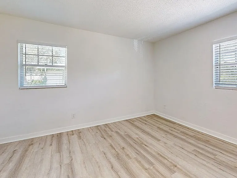 Bright and airy room with sleek hardwood floors and dual windows offering natural light.