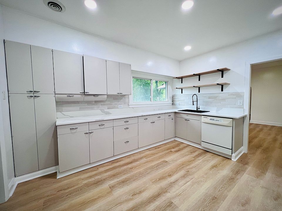 Kitchen & Storage: A bright kitchen featuring a large window, open shelving, and plenty of cabinetry, beautifully upgraded with brand-new white quartz countertops, LVP flooring, fresh paint, and modern recessed lighting.