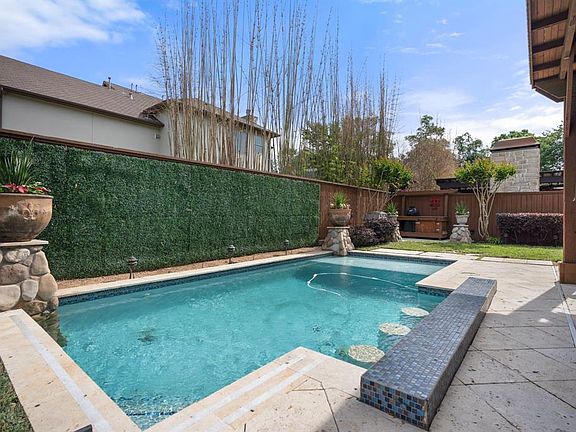 Heated pool with built in bar stools, tanning ledge, and decorative planters.