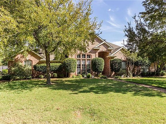 This home has a 3 car garage with the driveway on the side and an iron gate.