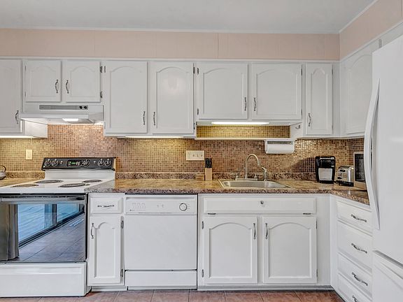 This stylish kitchen shines with it's white cabinets, glass tile backsplash and under counter lighting.