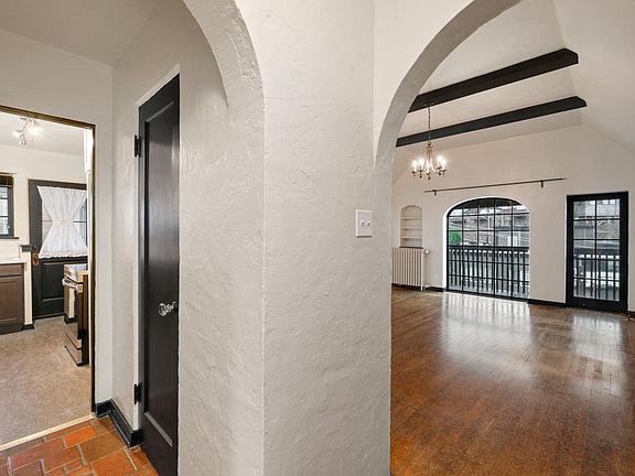 Main hallway with arched entries, view of the living room to a second hallway to the kitchen.