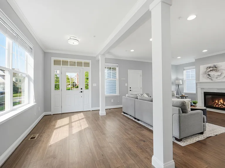 Beautiful entryway with tons of natural light, hardwood flooring and opening to the living room with gas fireplace.