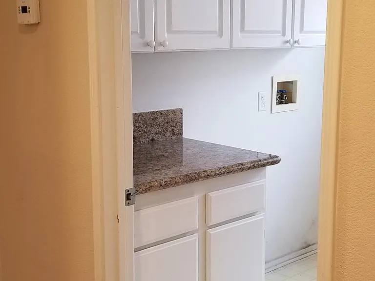 Upstairs laundry room with overhead cabinets, granite counter-top
