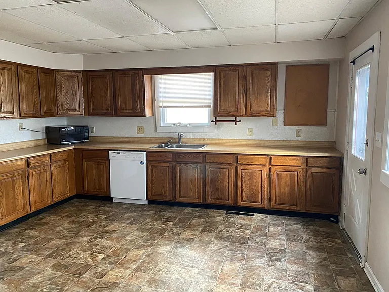 Look at all these cabinets AND counter space! Kitchen also has a small pantry with space to store your broom/mop. No more washing dishes in the sink, this house has a dishwasher. Door on right goes to backyard.