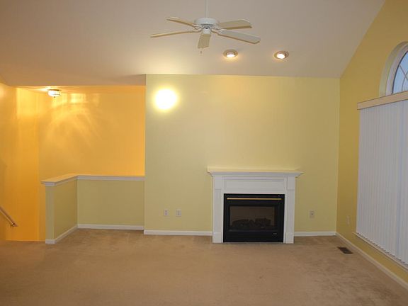 Gas fireplace, Ceiling fan in living room. cathedral ceiling