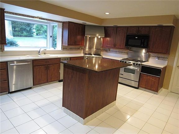 kitchen with solid surface counter tops/granite, stainless steel appliances, neutral tiled flooring with updated cabnitry