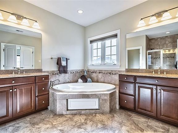 Relax in this spa bath with double vanities, sleek jetted tub, custom tile work, walk-in shower and separate commode room.