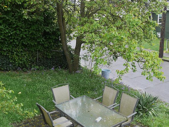 This stone patio is high above the sidewalk level, and under the massive and productive Asian pear tree! Available for gardening of roses, succulants. A few steps up to a deck is where there's an entrance to he house, Ample parking available on both str