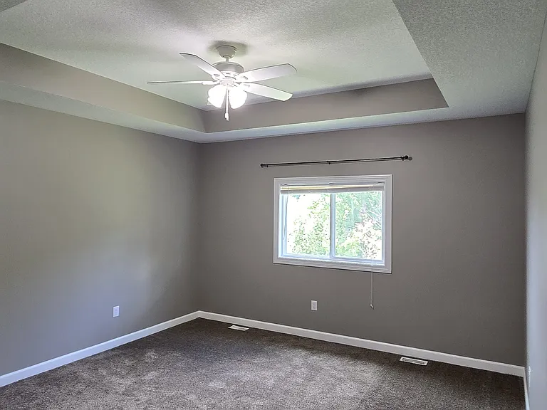 Master Bedroom with tray ceiling and ceiling fan.