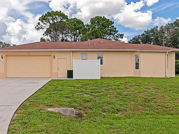 A high-utility garage with a large window, perfect for a workshop or extra storage, served by a wide double driveway. - 3890 Barbary Ln