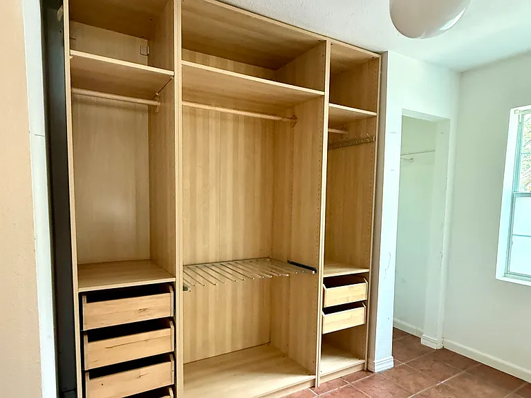 Custom closet setup plus additional clothes-hanging nook near window in oversized primary suite dressing area.