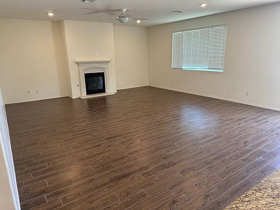 View of open concept family/living room with working fireplace and ceiling fan/light.