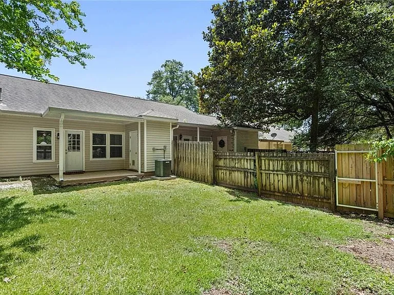 Expansive backyard featuring a covered patio, manicured lawn, and wooden privacy fencing