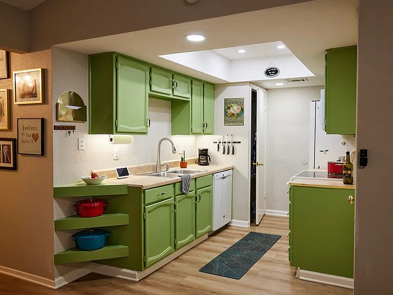 Kitchen with green cabinetry, dishwasher, light wood-style floors, light countertops, and recessed lighting