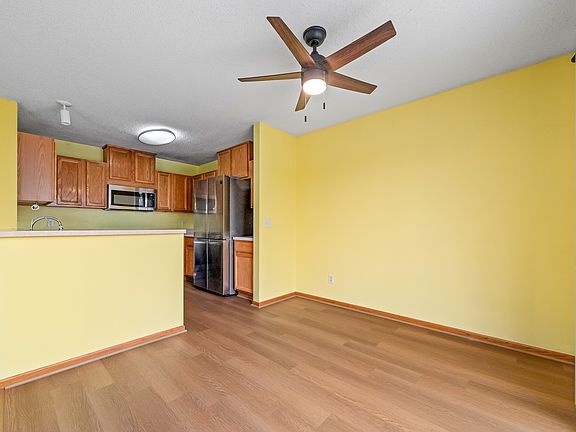 Dining room with ceiling light/fan. Kitchen has newer stainless steel appliances.
