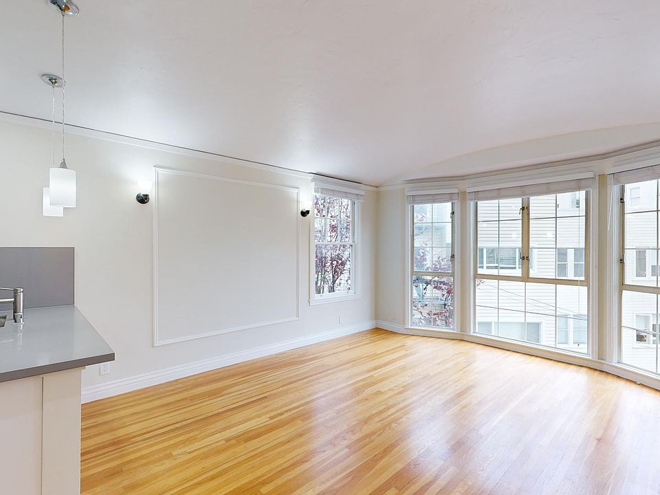 Living room with a large windows, wood-like floors, and a kitchen sink