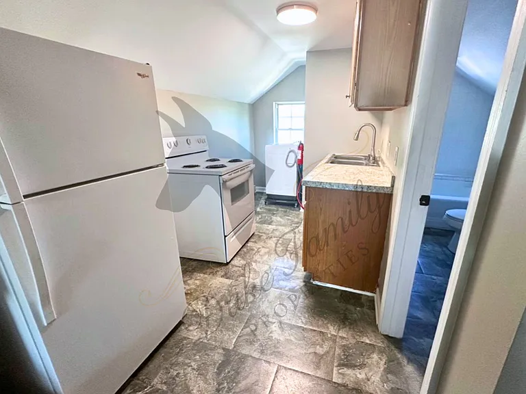 Kitchen with updated faucet and newly installed washer. Kitchen includes garbage disposal, refrigerator, and stove/oven.