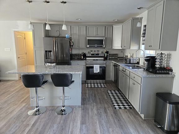 Showing better view of the kitchen and appliances, bar stools for the island, etc.
