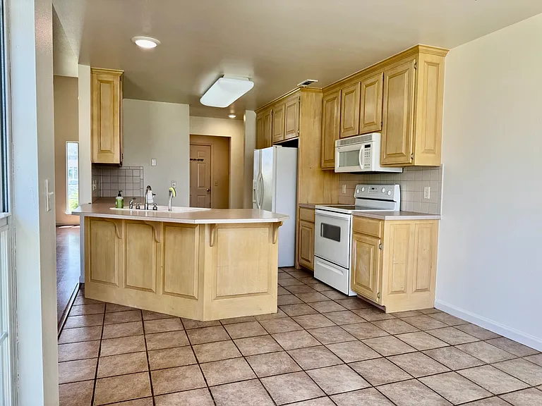 Kitchen from dining side _ full appliance package included: refrigerator, range, microwave, and dishwasher