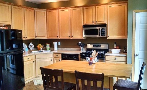 Central kitchen lined in maple cabinets, designer appliances, pantry and center island.
