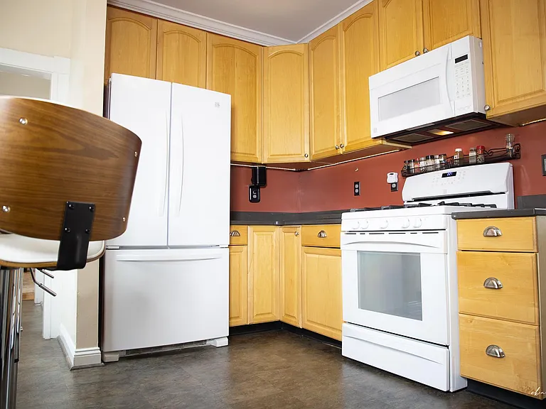 Gas stove with a vented microwave handing above and french door refrigerator.