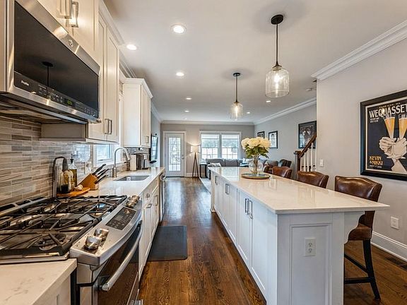 Open Floor Plan. Sunny Kitchen offers large Center Island with Breakfast Bar, Stainless Steel Appliances, and Ample Countertops and Cabinets. Powder Room is Adjacent.