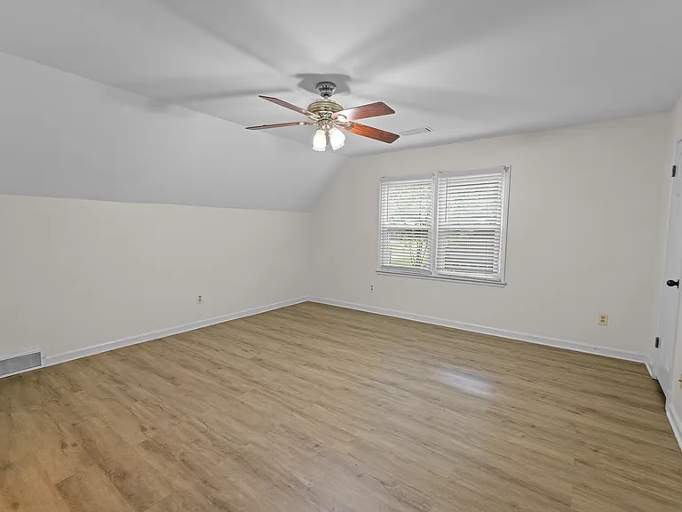 Charming bedroom with vaulted ceiling, ceiling fan, and warm hardwood floors _ bright and welcoming.