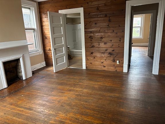 Living room with hardwoods floors, decorative fireplace and 3 windows