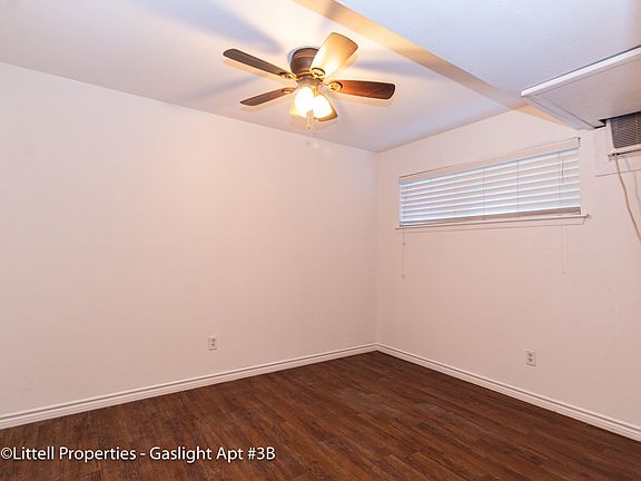 Bedroom 1: light wood flooring, ceiling fan, blinds, and AC unit