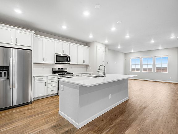 Gourmet kItchen with quartz countertops, white cabinetry and stainless steel gas appliances