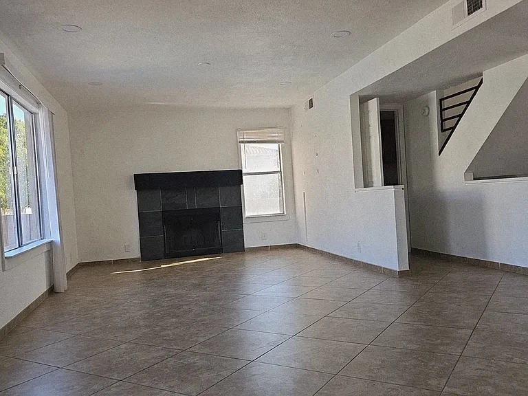 Spacious main living area featuring tile flooring, abundant natural light, and a cozy fireplace, all within an open and functional layout.