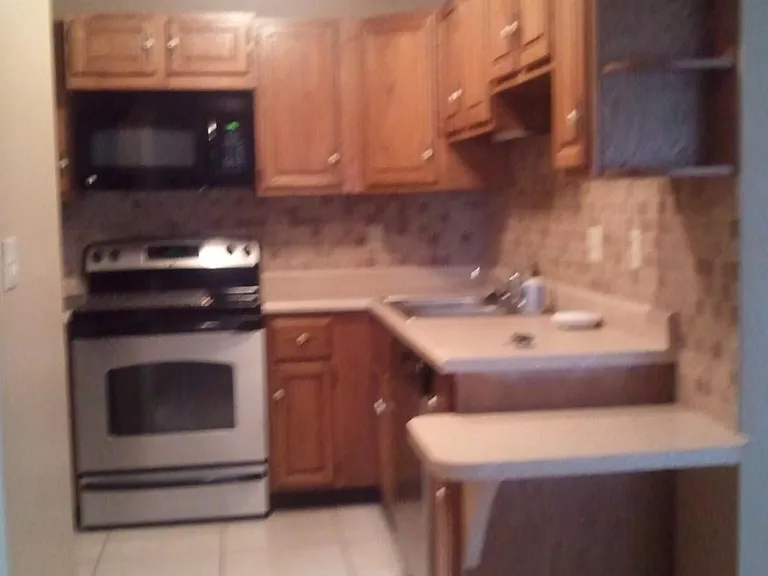 Kitchen with stainless steel appliances and tiled backsplash. View from laundry closet/second bath area.