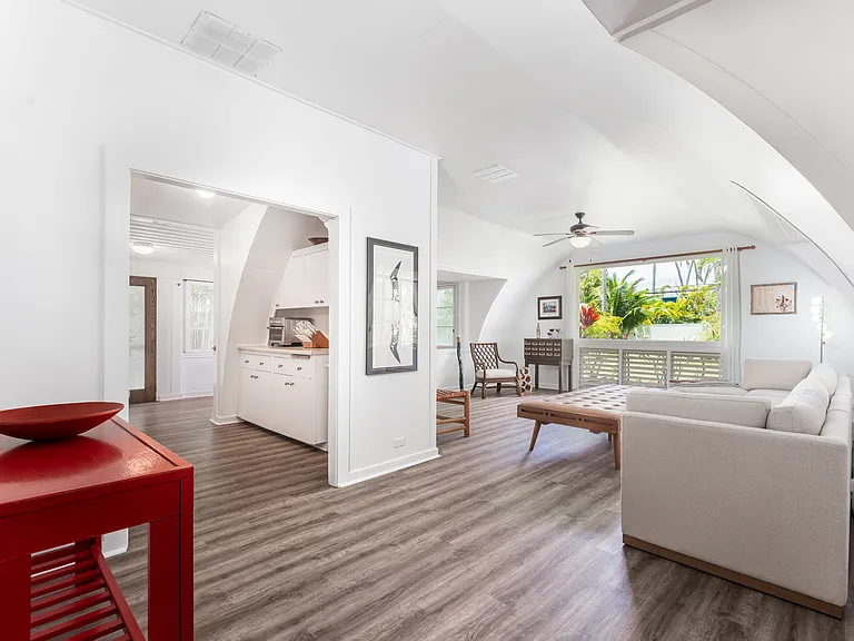 Spacious main living area featuring vaulted ceilings, abundant natural light, and tropical garden views.
