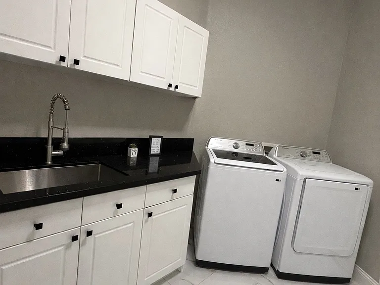 Laundry room with brand new smart washer and dryer with large laundry sink.