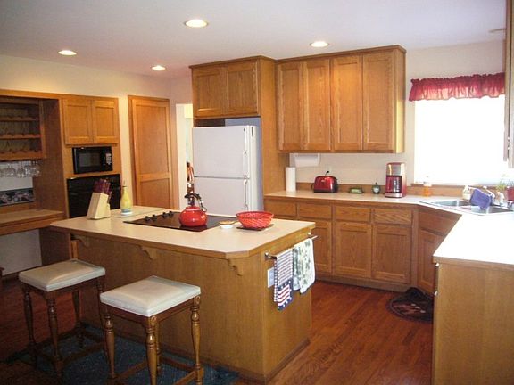 Kitchen has island, oak floor, wine rack and pantry.