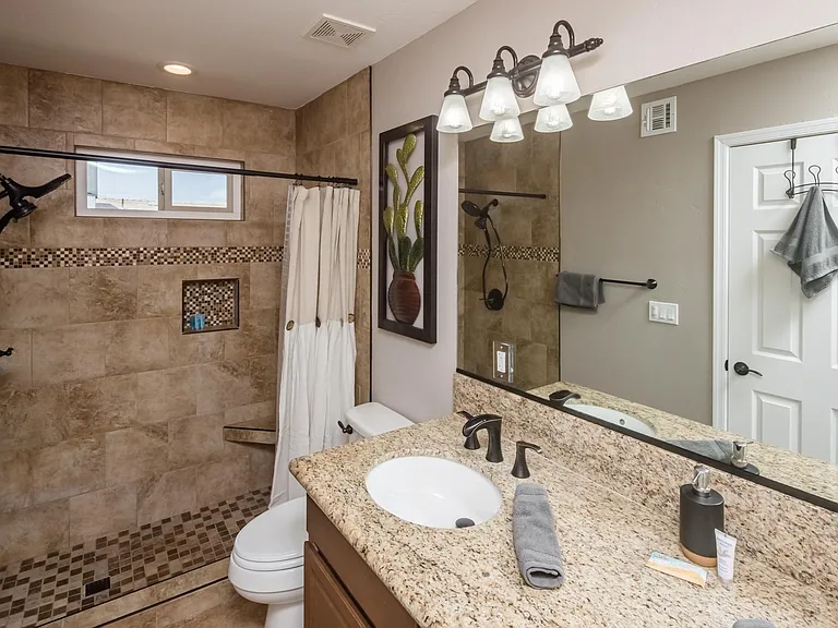 Updated Master bathroom featuring a tiled walk-in shower with decorative accent band, granite vanity, and modern fixtures.